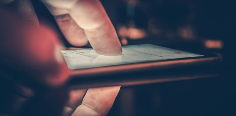 Playing Smartphone in a Dark. Male Finger on the Modern Smartphone Touchscreen Display. Browsing Internet on the Phone.